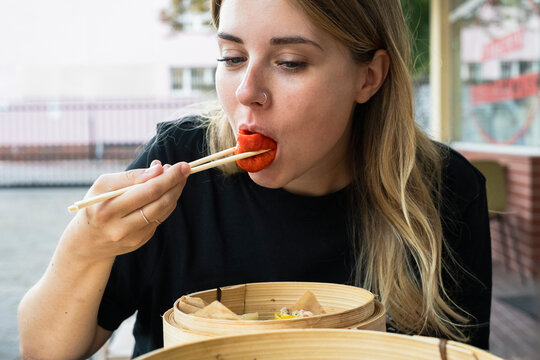 woman eating colorful dumplings with chopsticks