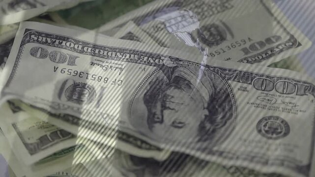 Dolly camera starting movement, revealing pile of US 100 dollar bills to show textures and serials