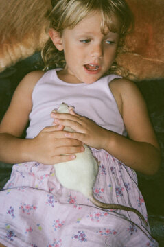 Young Girl Interacts With Pet Rat in a Cozy Indoor Setting