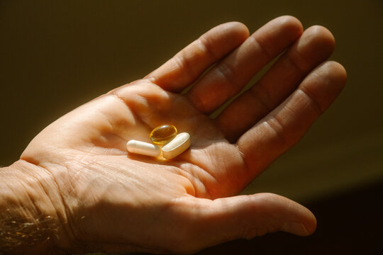 Man holding vitamin supplement pills in hand
