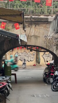 HANOI, VIETNAM &ndash; 29 November 2025: A view of motorbikes parked in Hanoi. Red flags hang above the street, and graffiti is on the walls. Old Quarter,.