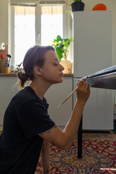Woman restoring furniture painting a table in her apartment