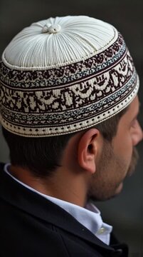 Man from behind showcasing an ornate white and dark patterned religious skullcap