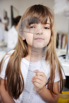 A little girl with transparent ruler against her face.