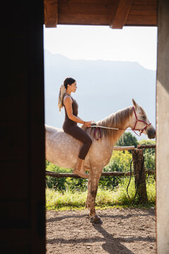 Woman Sitting Bareback on Horse Framed by Stable Door
