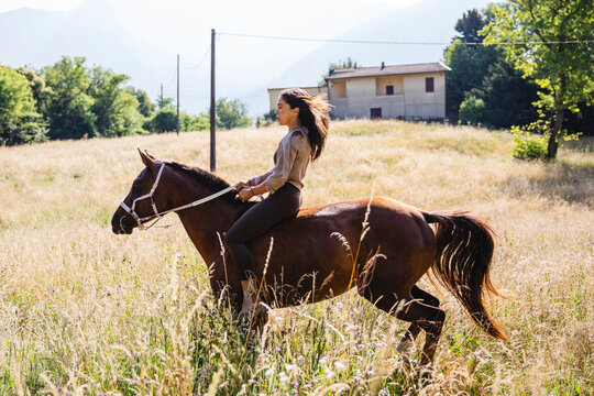 Woman Riding Horse Bareback Through Meadow