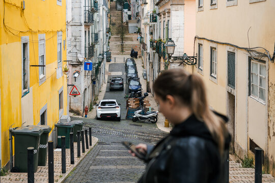 A woman looking at her smartphone on the street in Lisbon 