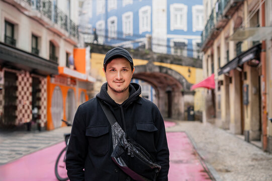 man in black casual outfit standing on colorful pink street in Lisbon