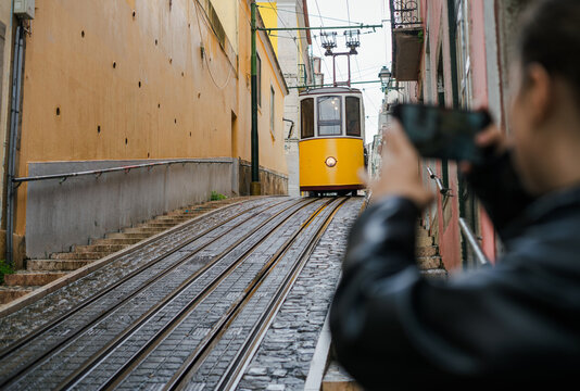 Woman taking a picture of a famous yellow funicular in Lisbon