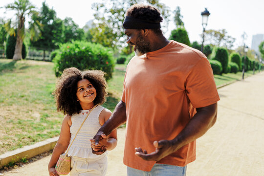 Father and daughter holding hands walking in park