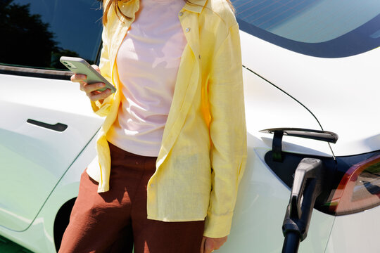 Woman on mobile phone While Electric Car Charges