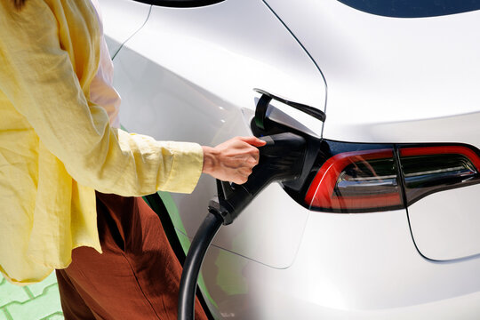Woman Hand Plugging EV Charger into Electric Car