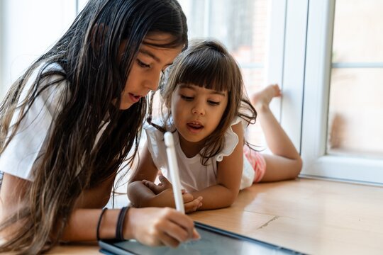 sisters using digital tablet and stylus