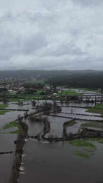 Vertical shot of river floodings event on the wide valley with farming fields and roads submerged. Natural disaster.