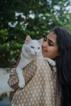 Woman Holds White Cat in Her Arms in a Green Outdoor Setting