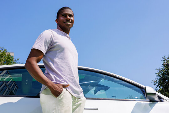 Smiling Driver Leaning on White Car, background blue sky