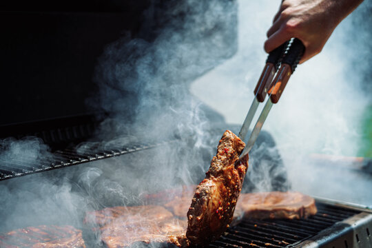 Grilling juicy beef steaks on outdoor BBQ with smoke