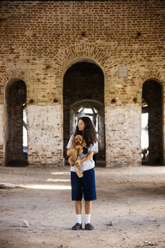 Young girl holds a dog in an old brick building