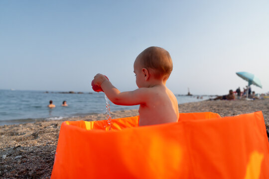 Baby playing with water in inflatable pool on beach