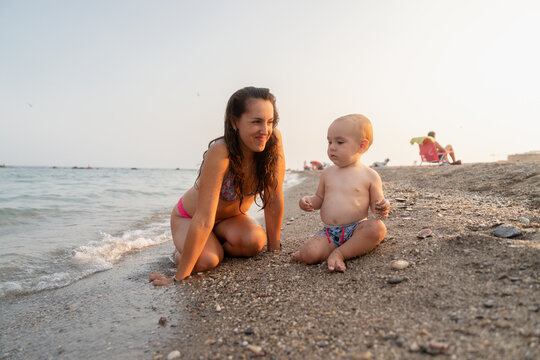 Mother and baby playing on the beach at sunset