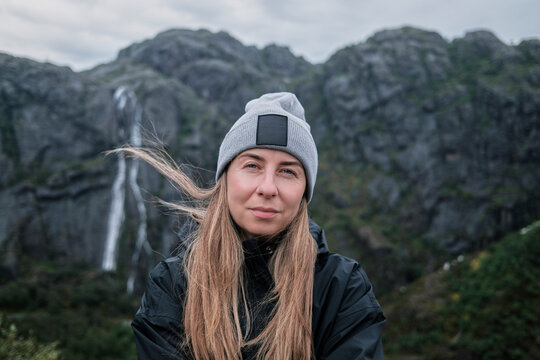 Woman Wearing Beanie Outdoors With Waterfall and Mountain Background