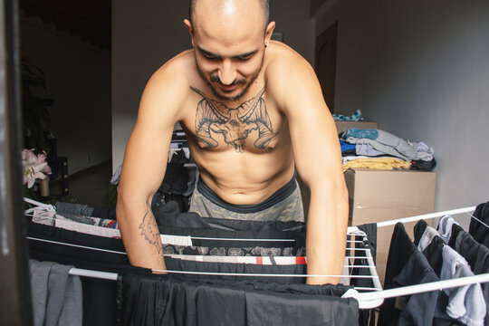 Man hanging laundry on a clothesline indoors in the afternoon