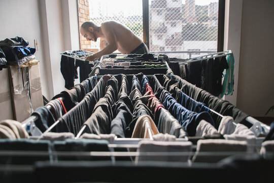 Man drying clothes indoors in urban apartment during daylight hours