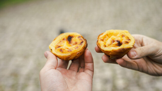 close-up of two hands holding pastel de nata