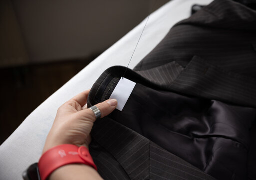 Close-up of the process of sewing a label onto a custom-made jacket.