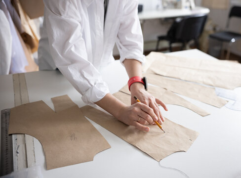 A close up of a hands making clothing patterns in atelier.