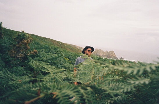 Man Walking Through Lush Green Ferns by the Coast