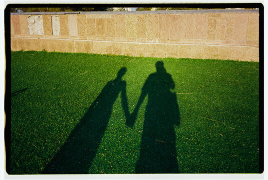 Shadows of Two People Holding Hands on Grass