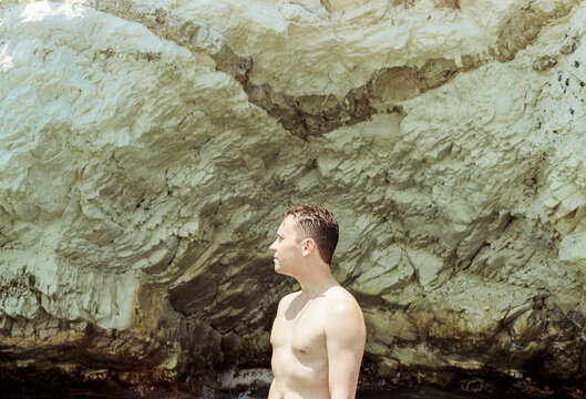 Man Standing by Rocky Shore During Sunny Day