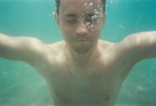Man Swimming Underwater While Holding His Breath in Clear Water