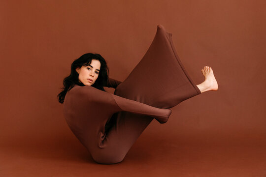Dancer performing flexible pose in brown dress 