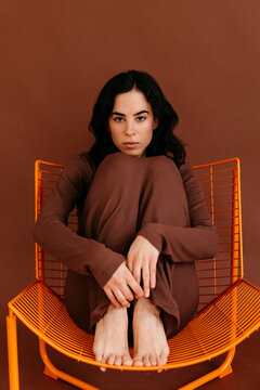 Woman sitting on orange metal chair showing flexibility