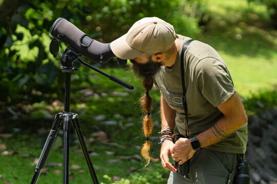 Photographer observing wildlife with spotting scope in nature