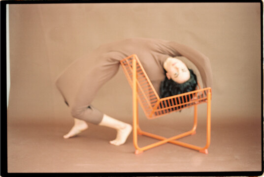 Blurry woman arching back over orange chair