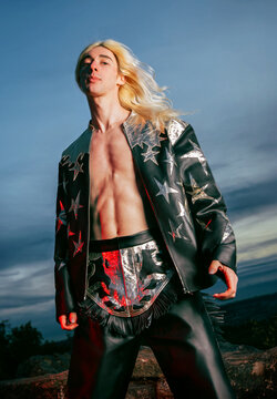 Young man in a black leather fringe suit at sunset in red flash light