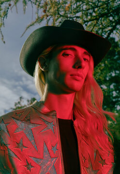 Portrait of a young man in a leather jacket and hat with a red flash