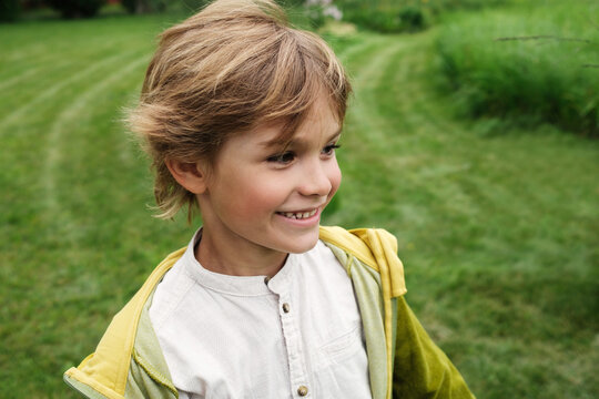 Young boy enjoys a sunny day outdoors with greenery all around 