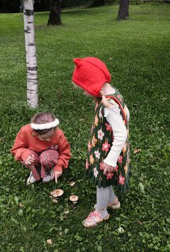 Two children explore mushrooms in a green park