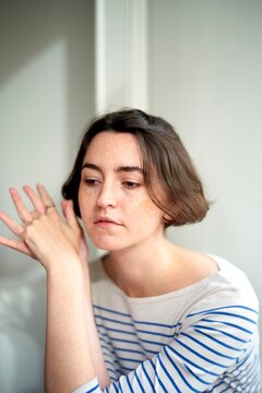 Woman in a Striped Shirt Lost in Thought in a Bright Space