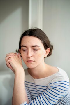 Thoughtful Woman in Striped Shirt Reflecting Indoors