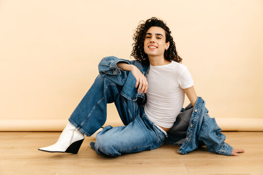 Queer model smiling and  wearing denim jacket and jeans