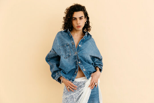 Queer model posing in denim jacket and lace skirt 