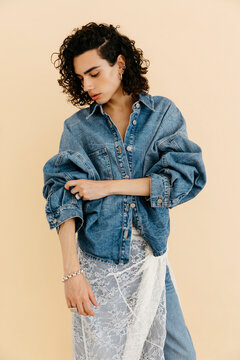 Queer model posing in denim jacket and lace skirt