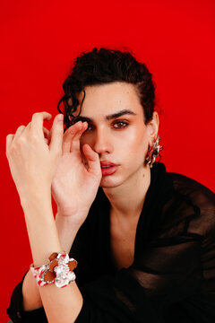 Queer man wearing modern jewelry on red background