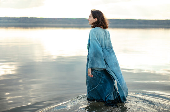 woman in blue dress by the water at sunset