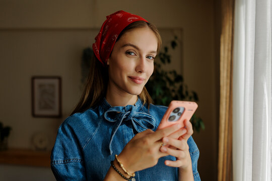 Smiling woman browsing smartphone at home